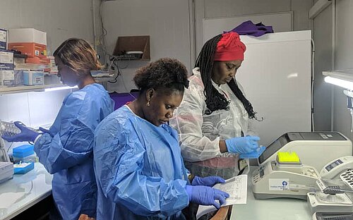 Three women preparing samples in a lab