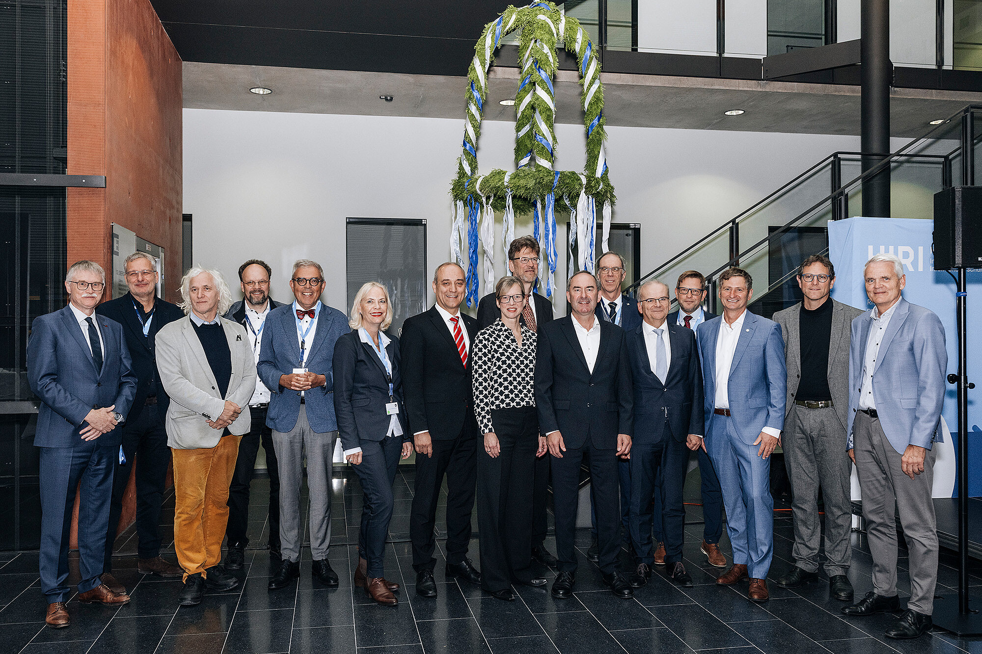 Gruppenbild mit 16 Personen, im Hintergrund die Richtkrone.