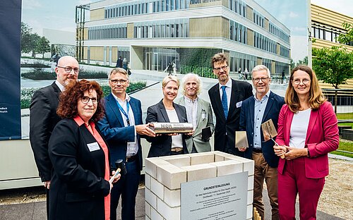 Group photo of eight persons behind a foundation stone