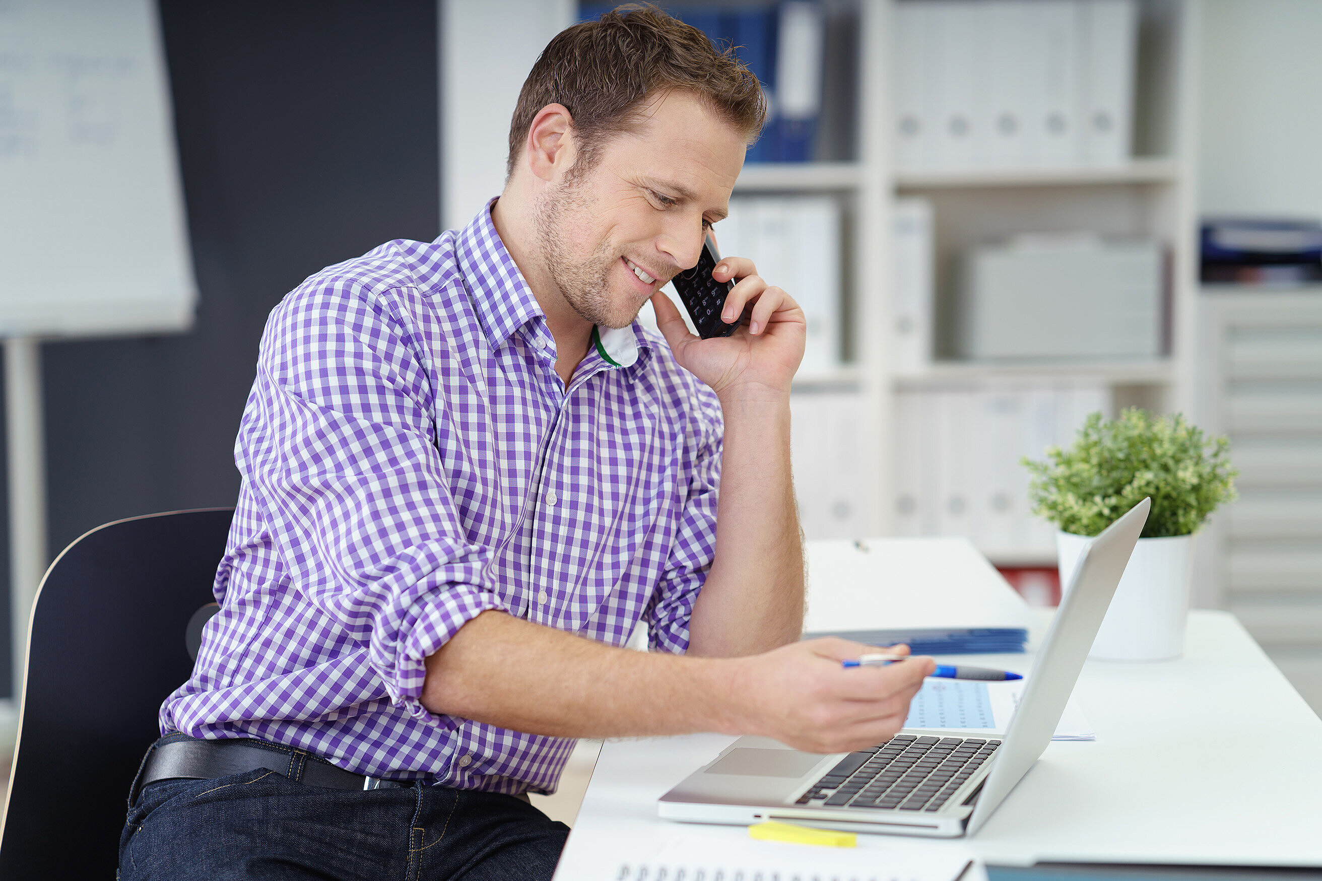 Mann arbeitet am Laptop und telefoniert