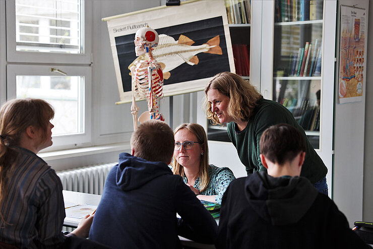 Two scientists working in groups with three pupils