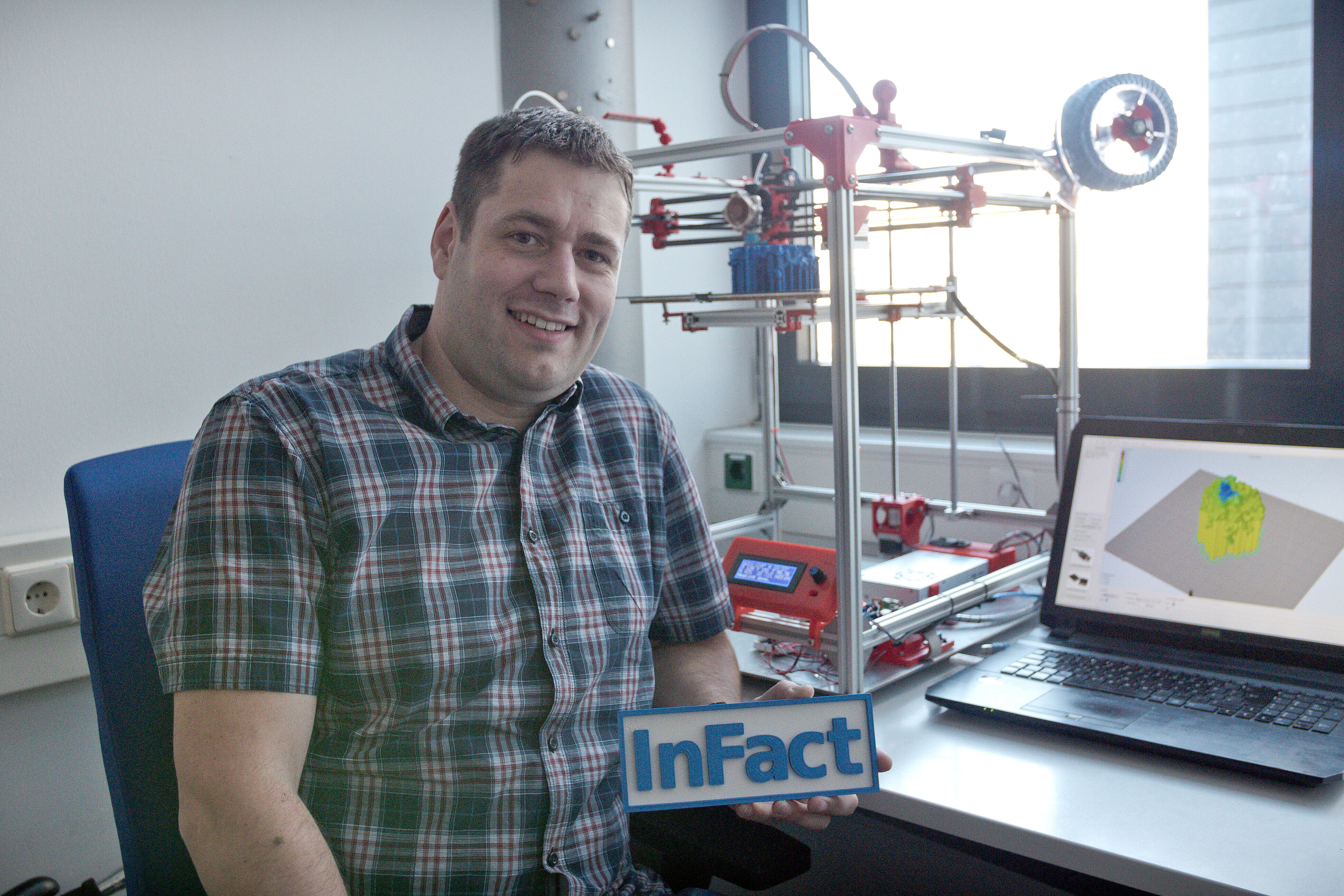 Stefan Schmelz am Schreibtisch mit 3D-Drucker und Laptop