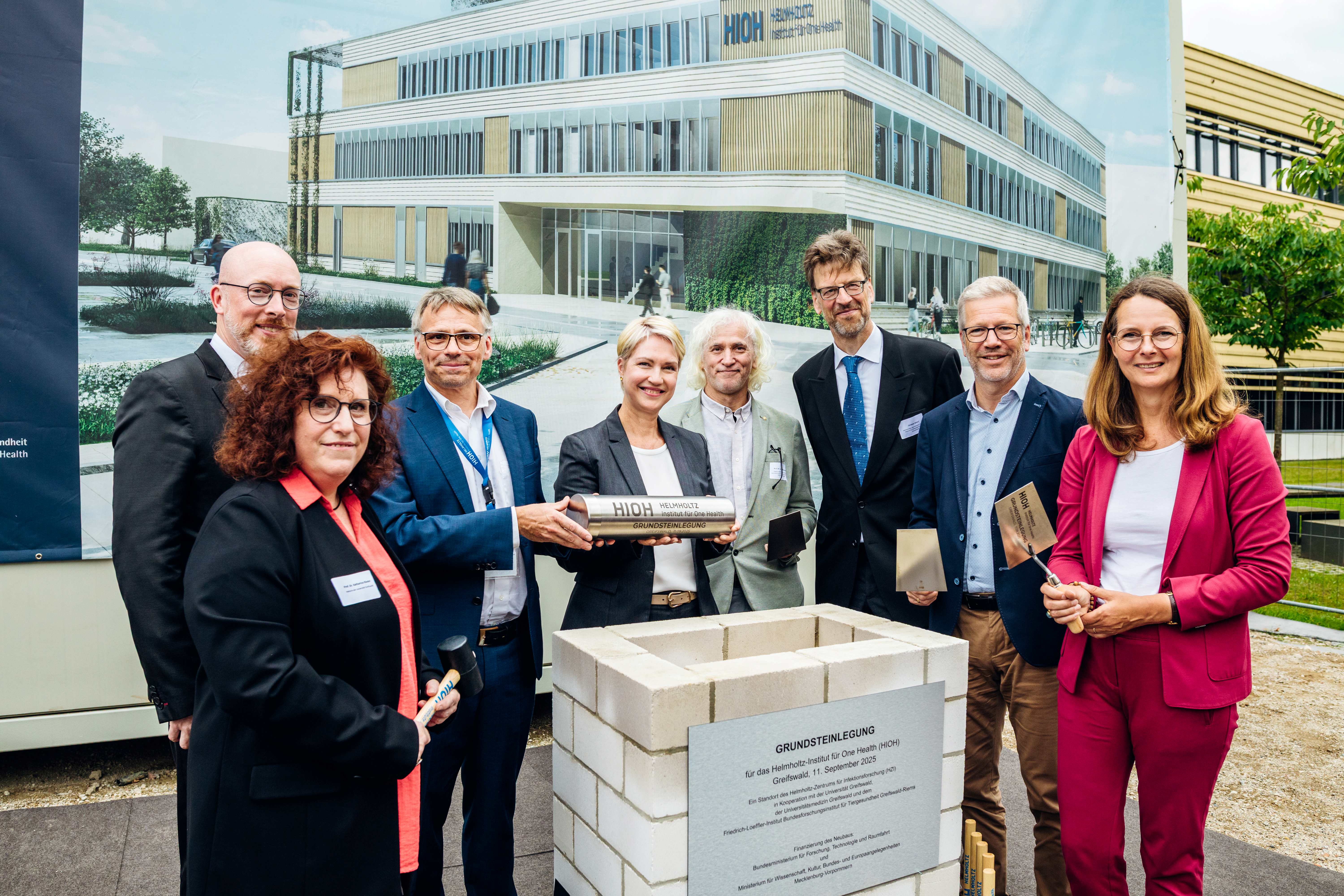Group photo of eight persons behind a foundation stone